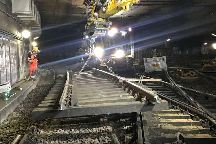 Gleis wird von einem Bagger in der Tunnelrhre angehoben