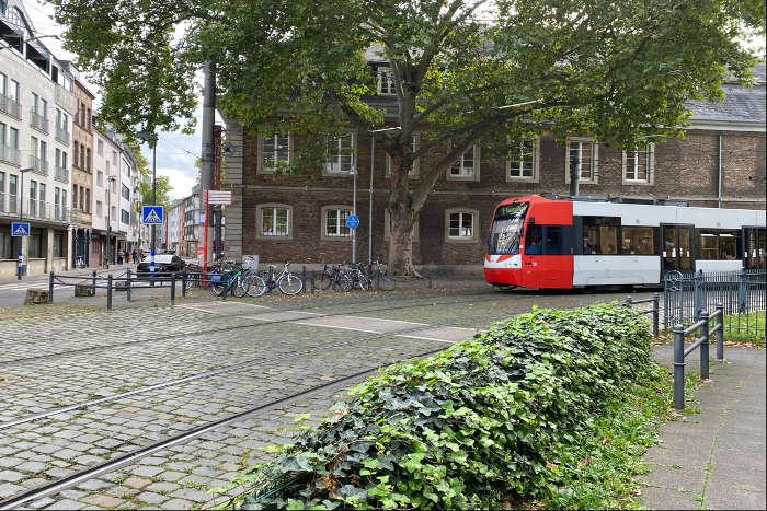 Randbegrnung an einer Strae mit historischem Kopfsteinflaster ber die eine Stadtbahn fhrt